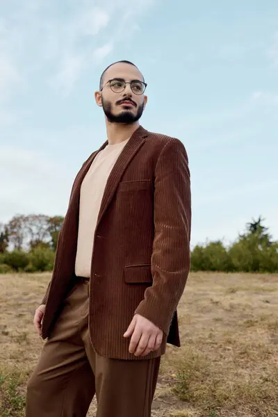 Ein gutaussehender Mann posiert anmutig in einem stylischen Herbst-Outfit inmitten einer wunderschönen Naturlandschaft. — Stockfoto