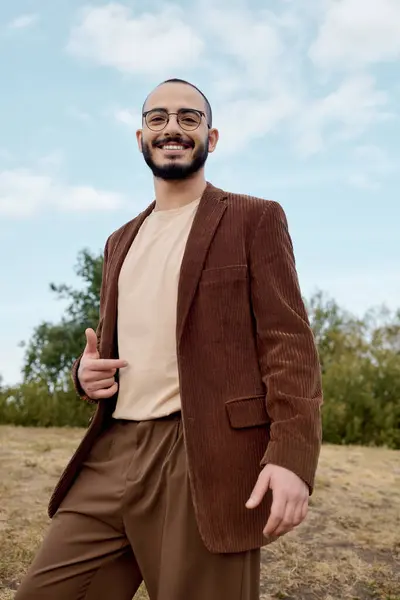 A well-dressed man showcases a warm autumn look while enjoying the tranquil beauty of nature. — Stock Photo