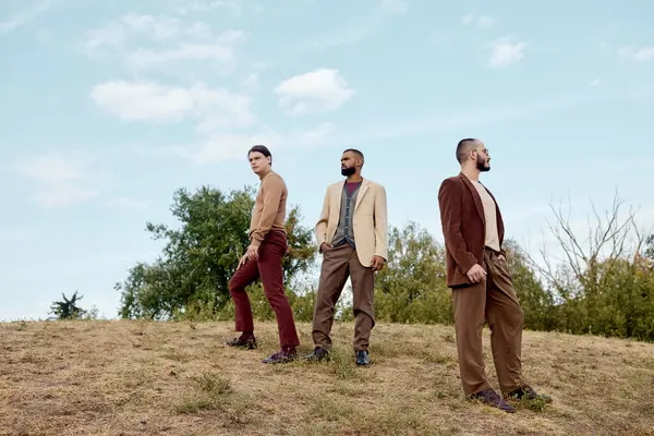 Três modelos masculinos elegantes posar em uma paisagem tranquila outono, exalando charme e elegância na natureza. — Fotografia de Stock