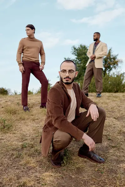 Trois hommes à la mode présentent une garde-robe d'automne à la mode tout en appréciant la beauté de la nature. — Photo de stock