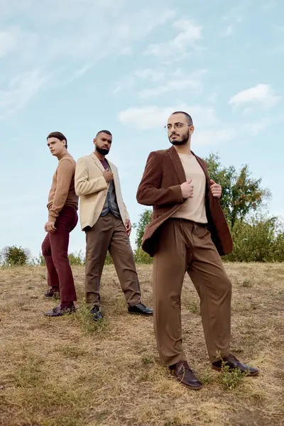 Three stylish men display their autumn fashion, standing confidently in a peaceful natural setting. — Stock Photo