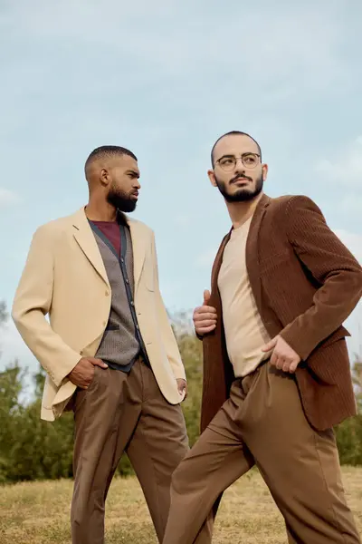 Homens bonitos mostram roupas chiques do outono enquanto posam confiantemente em uma paisagem serena e natural. — Fotografia de Stock