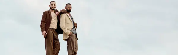 Deux hommes à la mode posent en tenue d'automne, entourés d'un champ paisible et coloré. — Photo de stock