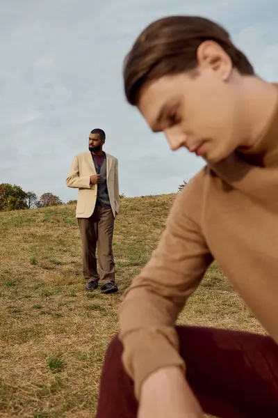 Deux beaux hommes portent des tenues d'automne tendance tout en profitant d'un moment paisible dans les champs. — Photo de stock