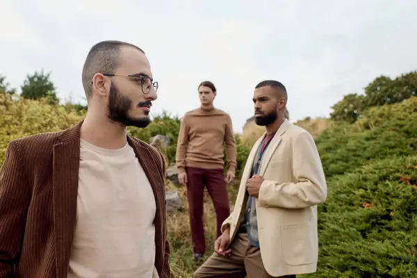 Três homens bonitos modelo roupas de outono na moda em um campo pitoresco cercado pela natureza. — Fotografia de Stock
