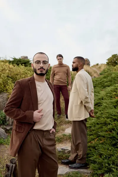 Three handsome men strike fashionable poses in a serene autumn field, showcasing stylish outfits. — Stock Photo