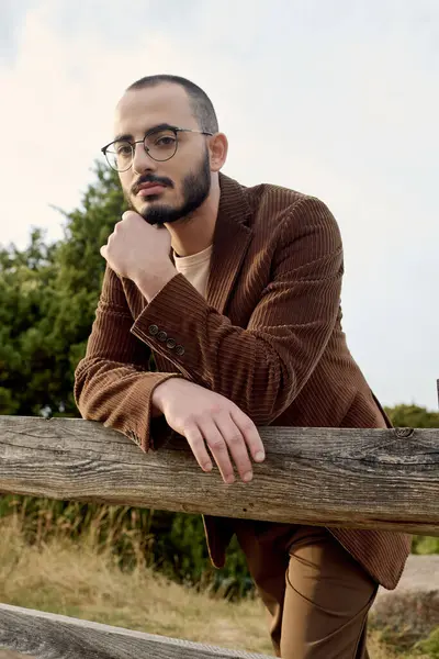A handsome man dressed in autumn attire reflects the tranquil beauty of nature around him. — Stock Photo