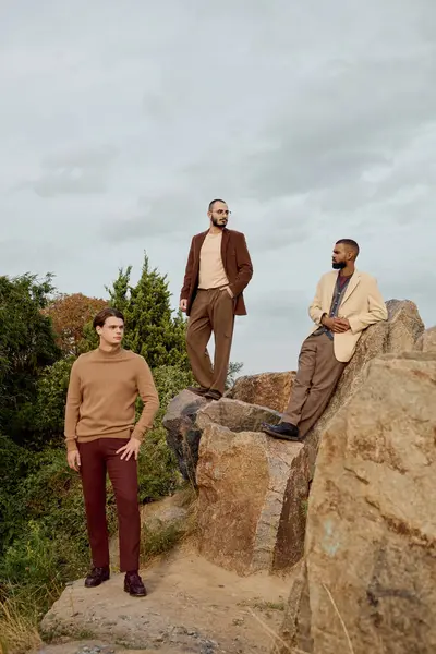 Três homens elegantes posar com confiança ao ar livre, apresentando roupas de outono na moda em um ambiente vibrante. — Fotografia de Stock