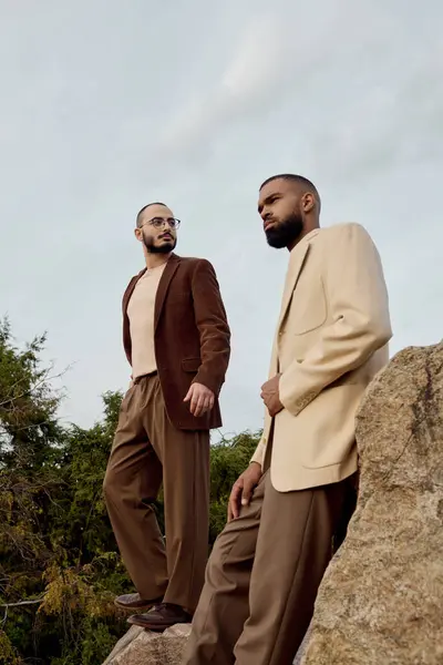 Handsome men pose in fashionable autumn attire, standing among lush greenery during a crisp fall day. — Stock Photo