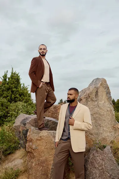 Zwei gut aussehende Männer modeln schicke Herbst-Outfits und posieren stolz in einer malerischen Outdoor-Umgebung. — Stockfoto