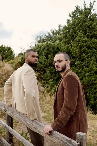 Two handsome men pose confidently in trendy fall attire amidst a serene autumn field setting. — Stock Photo