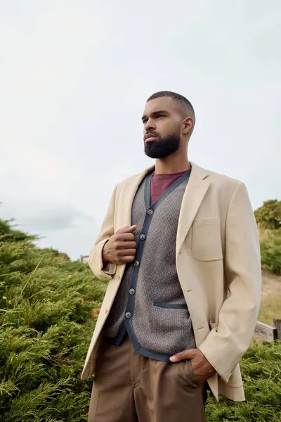 A handsome man stands confidently in a field, embracing autumn's beauty with his stylish attire. — Stock Photo