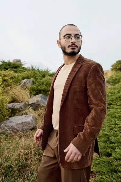 A well-dressed man stands confidently in a serene field, showcasing autumn fashion in a scenic setting. — Stock Photo