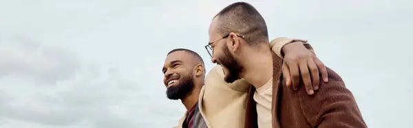 Deux hommes à la mode posent joyeusement dans un paysage automnal pittoresque, mettant en vedette des tenues vibrantes. — Photo de stock