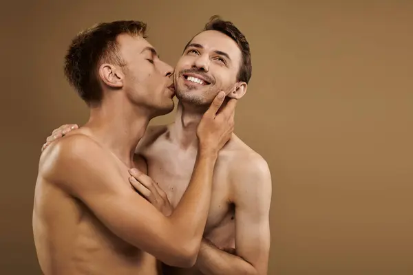 Two young men share a loving kiss, showcasing their affection and connection in a cozy atmosphere. — Stock Photo