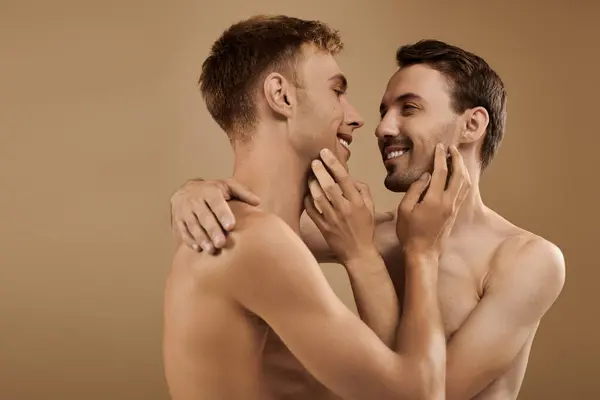 Two young men share a joyful embrace, radiating love and connection in a warm atmosphere. — Stock Photo