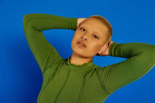 A stylish young woman radiates confidence, flaunting her unique look against a blue backdrop. — Stock Photo