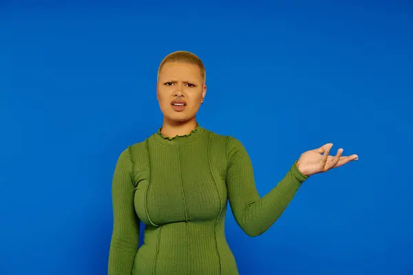 A young woman dressed in a form fitting green outfit expresses curiosity with a questioning gesture. — Stock Photo