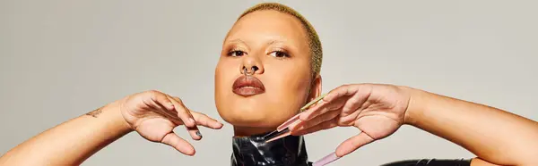 The young woman stands confidently, exuding bold fashion with striking features and unique pose. — Stock Photo