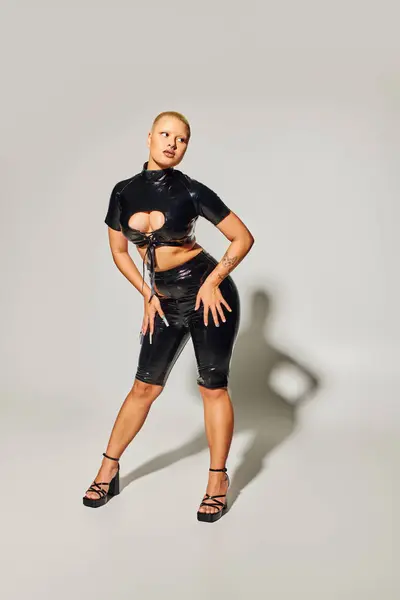 A fashionable young woman showcases bold style with a striking look in a chic studio backdrop. — Stock Photo