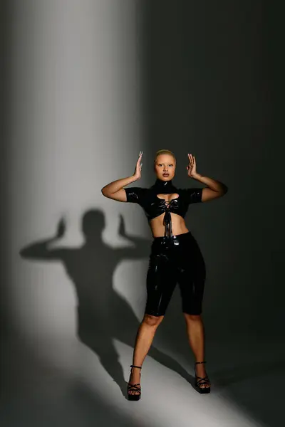 A fashionable young woman showcases her style with bold poses and striking shadows in the studio. — Stock Photo