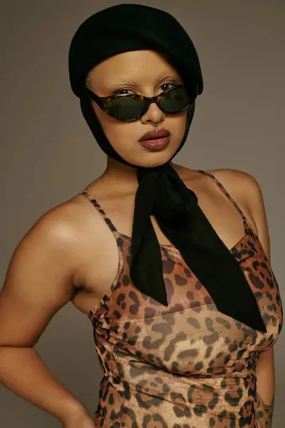 A young fashionable woman stands boldly in a leopard print ensemble, showcasing her unique style. — Stock Photo