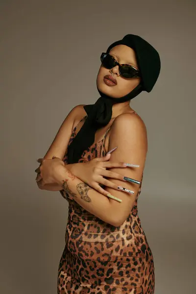 A fashionable young woman displays her unique style wearing a leopard print dress and accessories. — Stock Photo