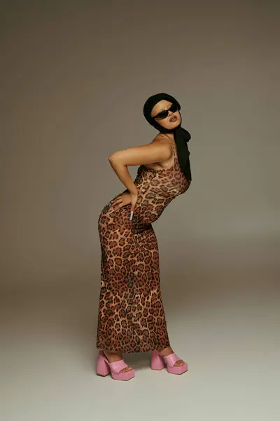La joven posa con confianza en un vestido estampado de leopardo, exudando estilo y actitud. - foto de stock