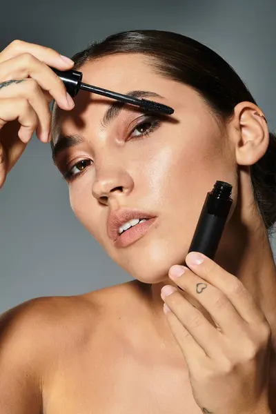 A striking woman enhances her eyes with mascara, showcasing beauty and poise during twilight hours. — Stock Photo