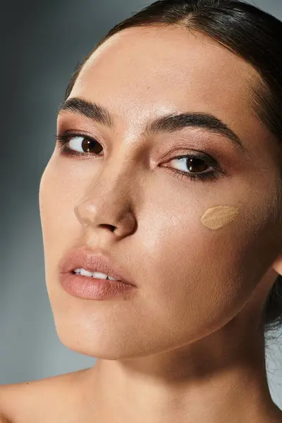 The beautiful woman applies foundation gracefully while demonstrating makeup artistry skills. — Stock Photo