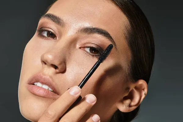 A lovely woman applies mascara with focus, showcasing her artistic makeup skills and elegance. — Stock Photo