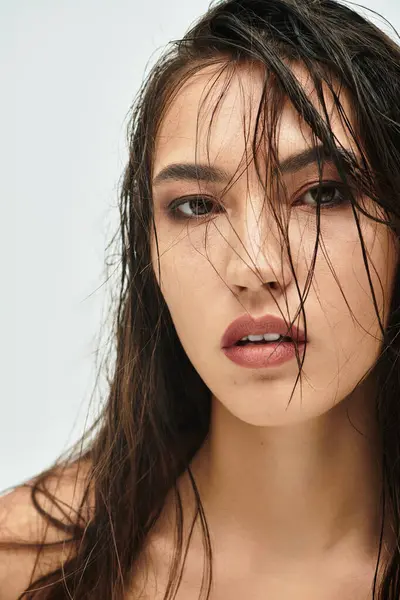 Una donna accattivante con lunghi capelli bagnati guarda direttamente lo spettatore, trasudando fiducia e bellezza. — Foto stock
