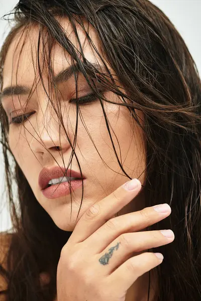 Uma mulher deslumbrante com cabelo molhado em cascata acaricia suavemente seu rosto, exalando elegância. — Fotografia de Stock