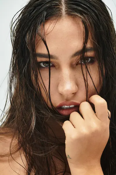 Un primer plano muestra a una mujer con el pelo mojado, destacando su cautivadora mirada y belleza. - foto de stock