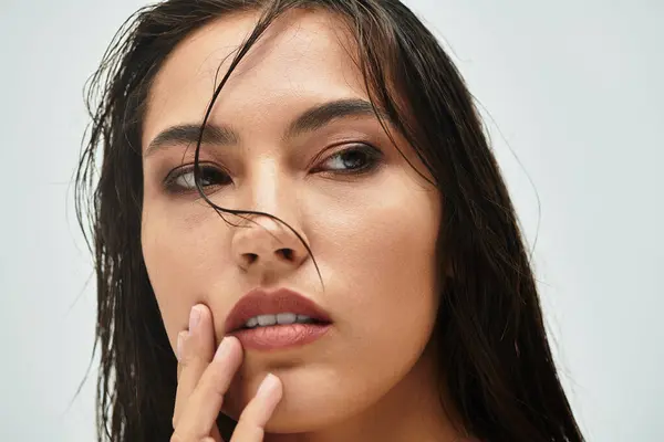 A woman with wet hair gently touches her face, lost in contemplation and beauty. — Stock Photo