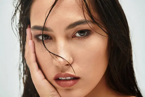 A beautiful woman gazes intensely while softly touching her face, showcasing elegance. — Stock Photo