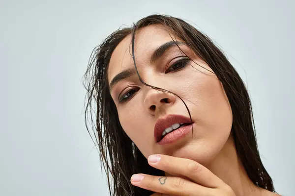La donna accattivante con i capelli bagnati e un'espressione morbida si impegna direttamente con lo spettatore — Foto stock