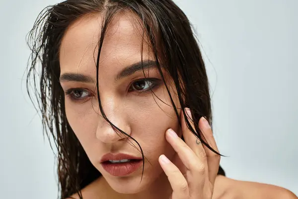A woman gently touches her face while revealing her captivating features and charm. — Stock Photo