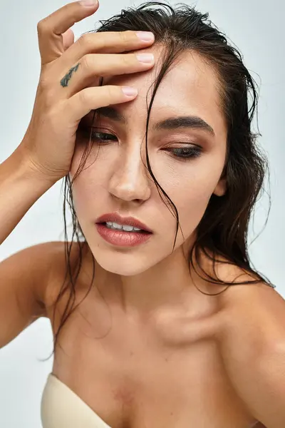 Eine atemberaubende Frau posiert mit nachdenklichem Gesichtsausdruck vor minimalistischem Hintergrund. — Stockfoto