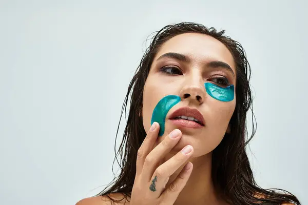 A woman is putting on skincare patches, focusing on her self care routine at home. — Stock Photo