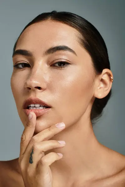 A stunning woman showcases her beauty and poise, gently touching her lips with finesse. — Stock Photo
