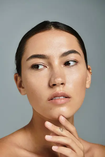 A stunning woman with a soft expression contemplates in a serene studio, showcasing her beauty. — Stock Photo