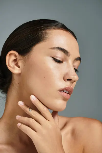 A beautiful woman showcases her natural beauty, placing her hand gently on her face. — Stock Photo