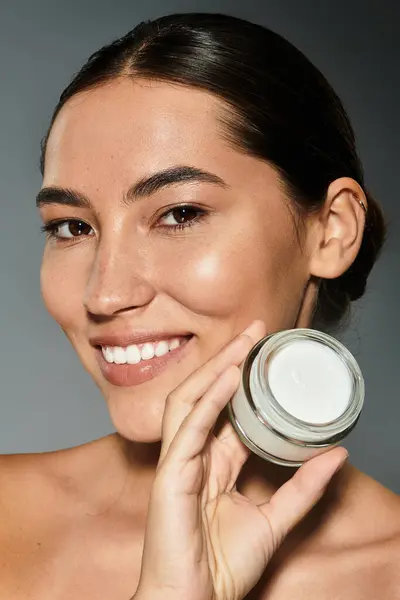 A smiling woman proudly presents her favorite skincare cream, glowing in natural light. — Stock Photo