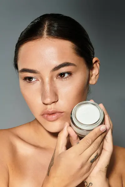 Une femme souligne sa routine de soins de la peau, tenant un produit naturel avec confiance. — Photo de stock
