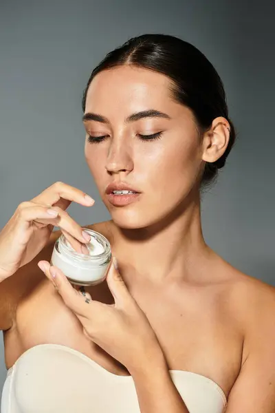 A mulher está gentilmente aplicando um creme em seu rosto, mostrando beleza e graça. — Fotografia de Stock
