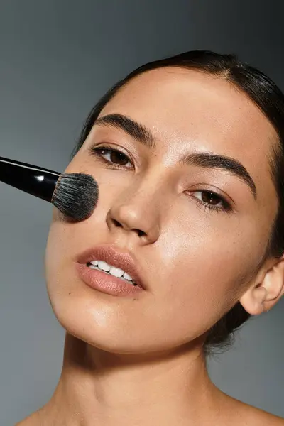 Una artista de maquillaje aplica cuidadosamente los cimientos en la cara de una mujer para resaltar sus rasgos. - foto de stock
