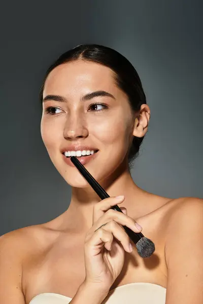 A woman enjoys applying makeup with a brush, radiating joy and confidence in a serene atmosphere. — Stock Photo