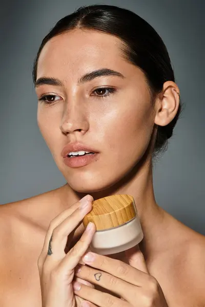 A graceful woman holds a skincare jar, her expression reflecting beauty and confidence. — Stock Photo