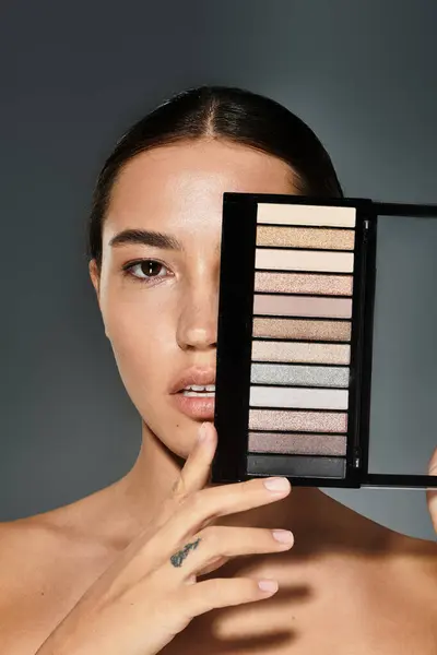 The beautiful woman holds an eyeshadow palette while highlighting her artistic side. — Stock Photo